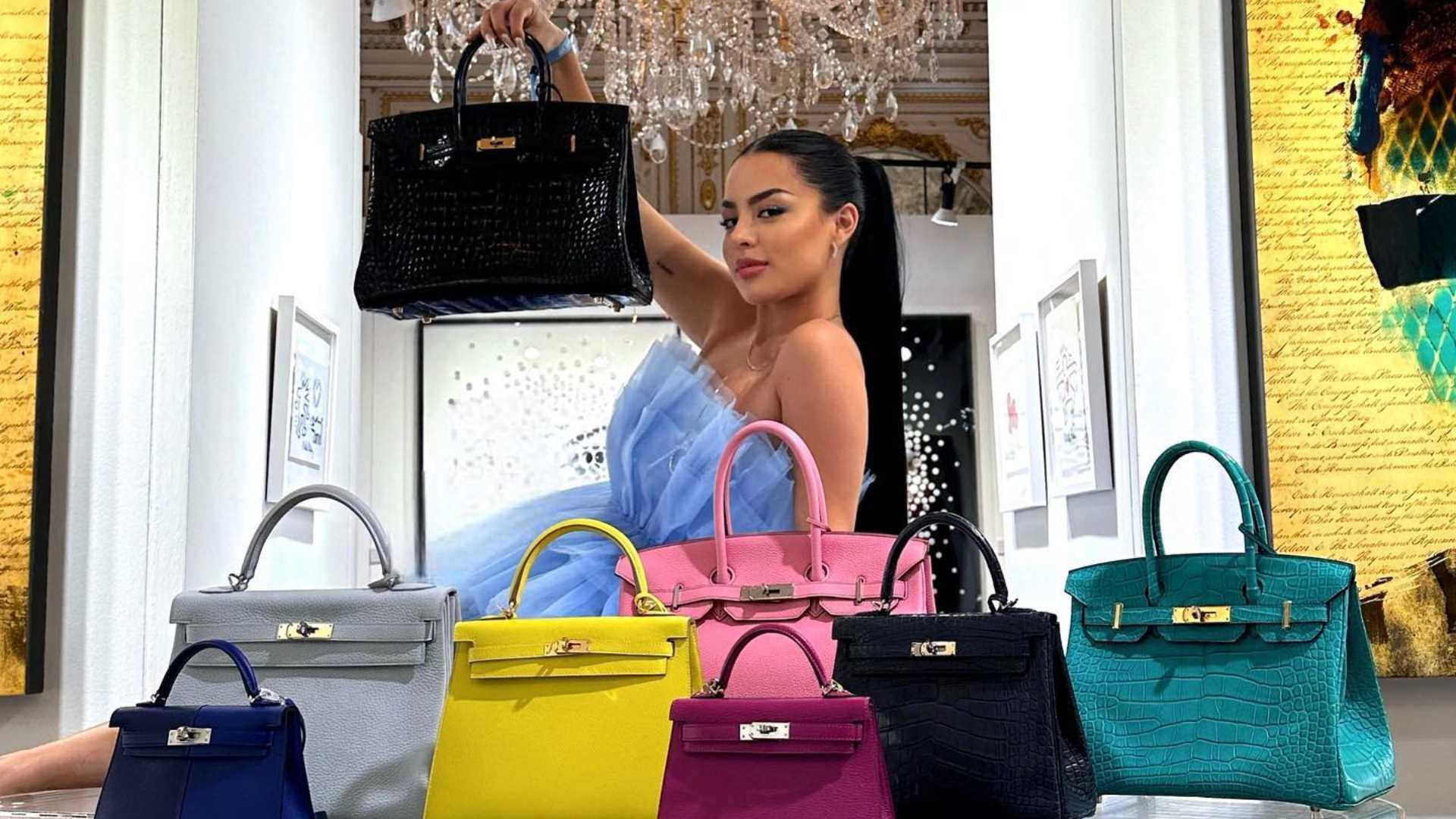 An elegant model stands amidst an extensive collection of Hermes and Chanel handbags. The luxurious bags, varying in sizes and colors, are meticulously arranged around her, showcasing their unique designs and high-quality craftsmanship. The model, dressed in sophisticated attire, gracefully poses with one of the handbags, accentuating the exclusivity and prestige of the collection